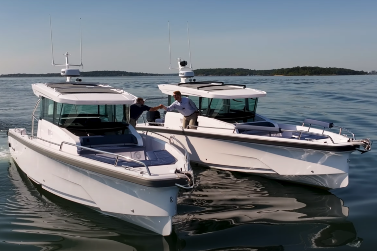 Two Axopar 29s abreast in the water with Yacht Consultants Mike Porter (Portsmouth, RI) and Ben Scheffer (Camden, ME) shaking hands over the water between the boats, filmed from in front during a twin-engine vs single-engine race.