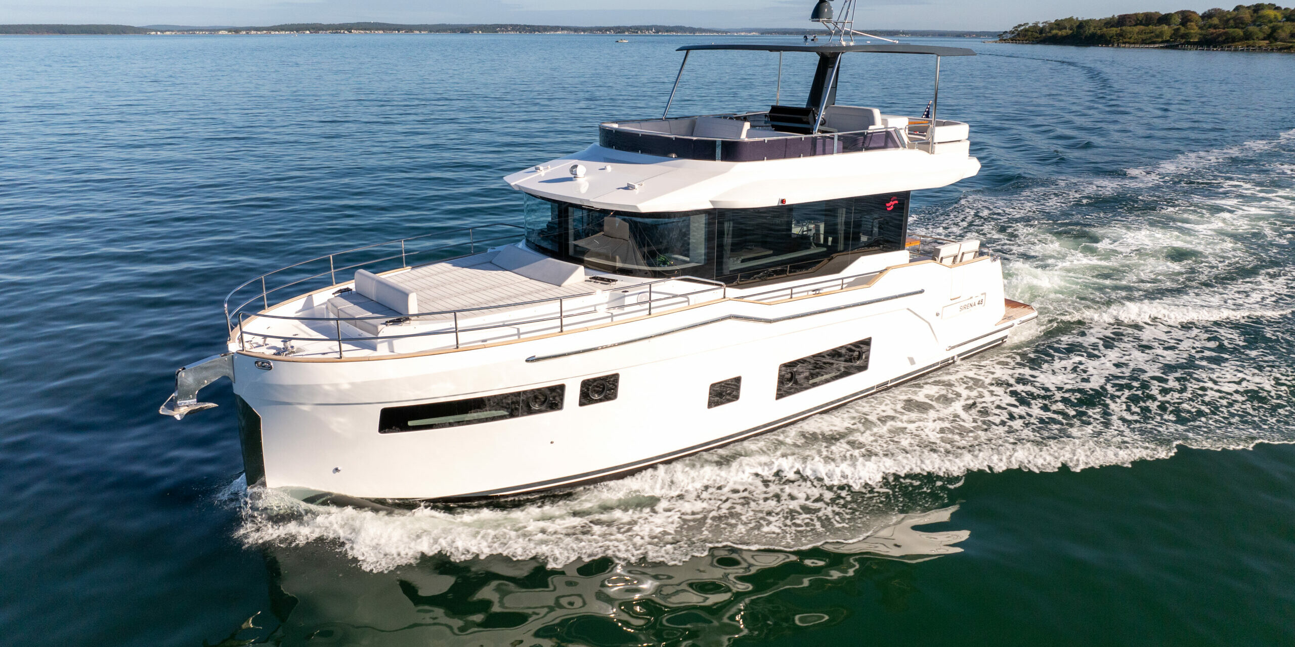Forward port-side view of Sirena 48 flybridge cruising through green waters.