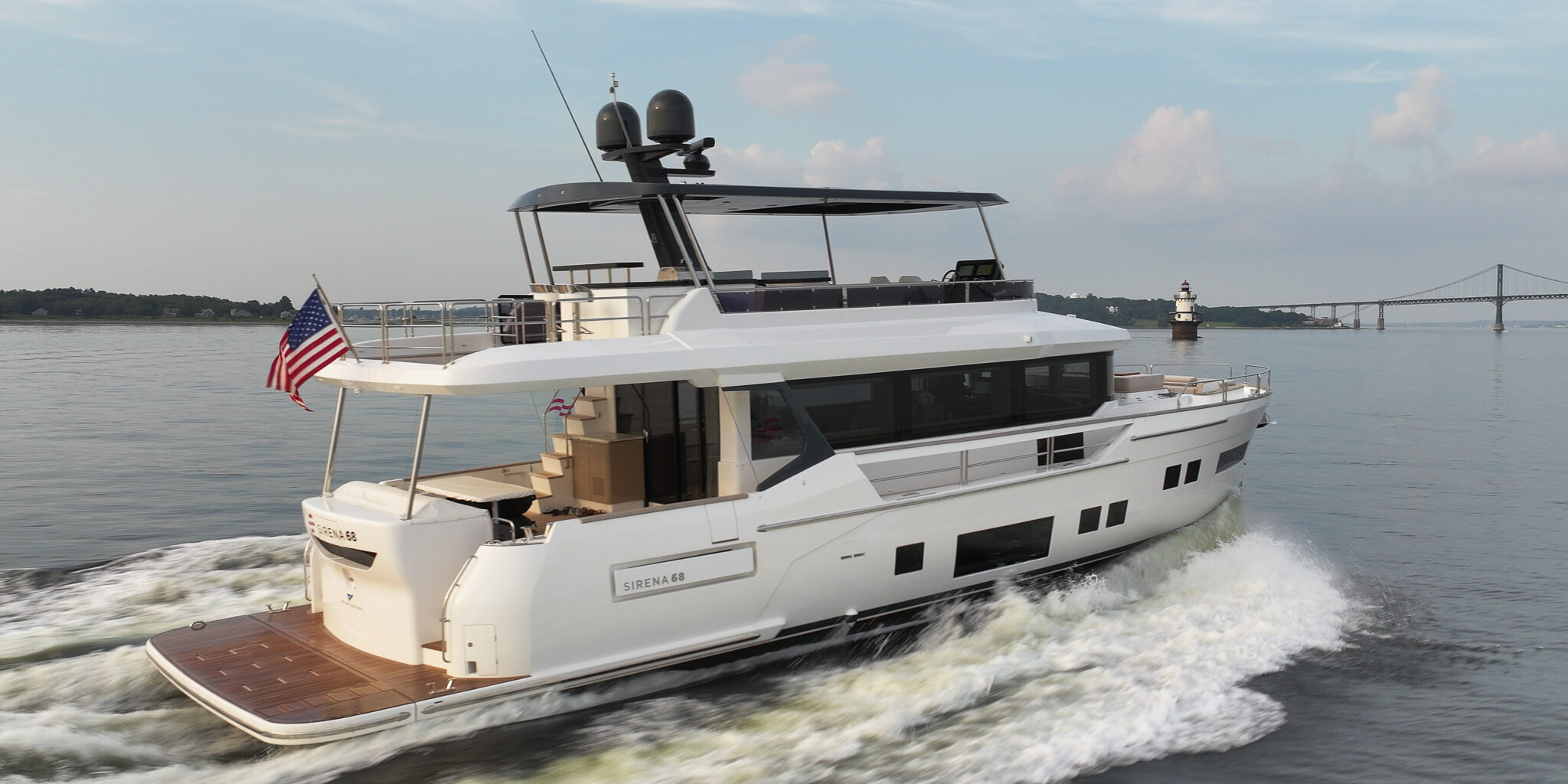 Sirena 68 cruising in Newport, Rhode Island with a flybridge and an American flag flying from the stern.