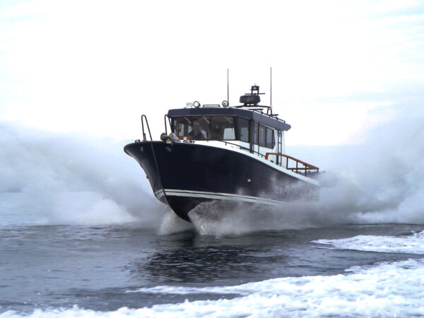 Targa 32 cruising through Casco Bay, Maine with bow up and spray on both sides, captured from water level.