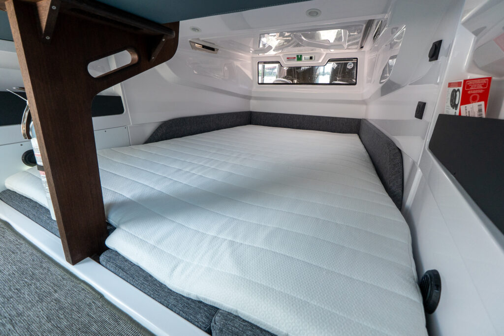 Inside the Axopar 29 XC Cross Cabin BRABUS Edition aft cabin showing a large double berth with quilted mattress, side bolsters, and a wood step/ladder at the entrance.