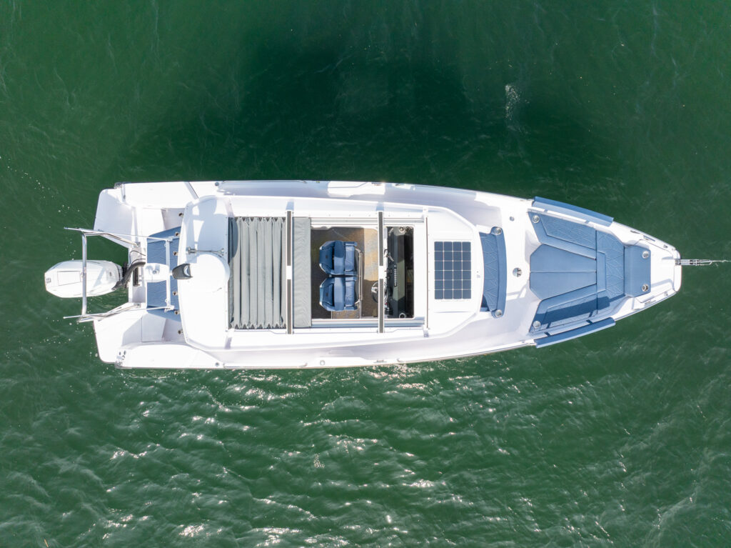 Aerial view of an Axopar 29 XC Cross Cabin showing the bow seating with Sphere upholstery, sliding roof, helm seating, aft cabin sunpad, and single Mercury V10 Verado outboard.