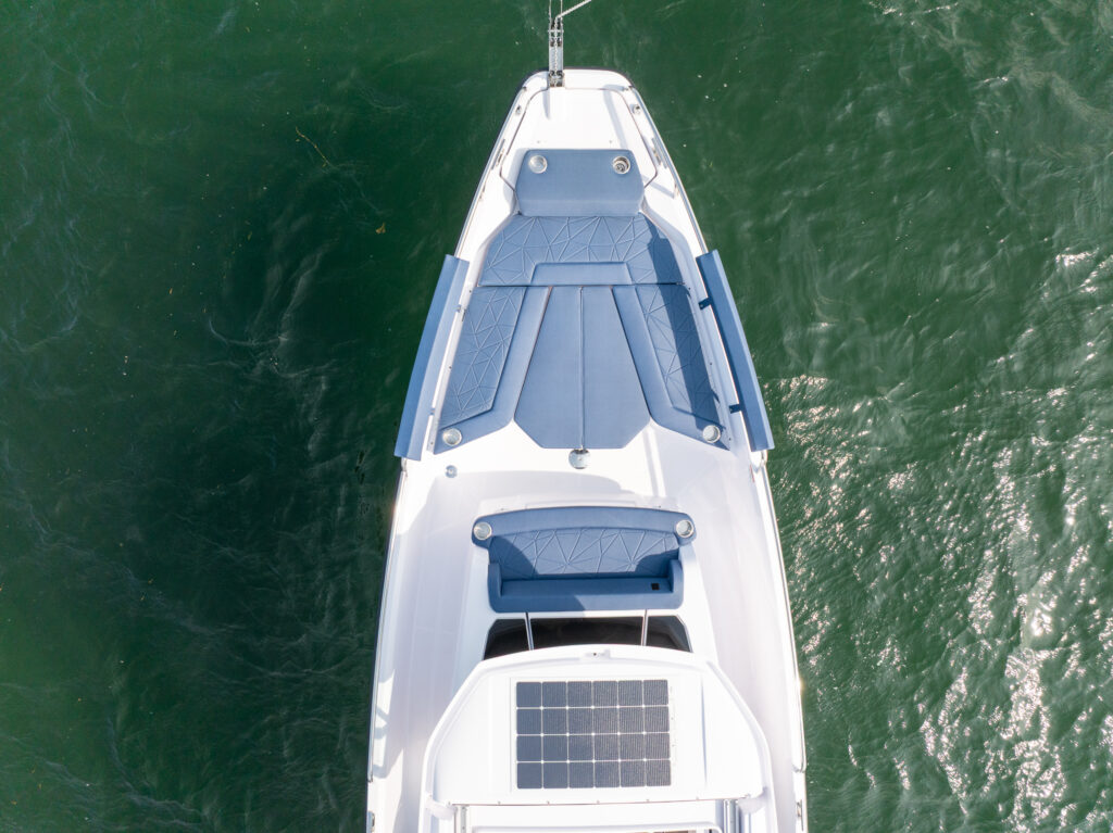 Aerial view of the Axopar 29 XC Cross Cabin’s bow seating with Sphere upholstery, showing the sunpad layout and surrounding green water.