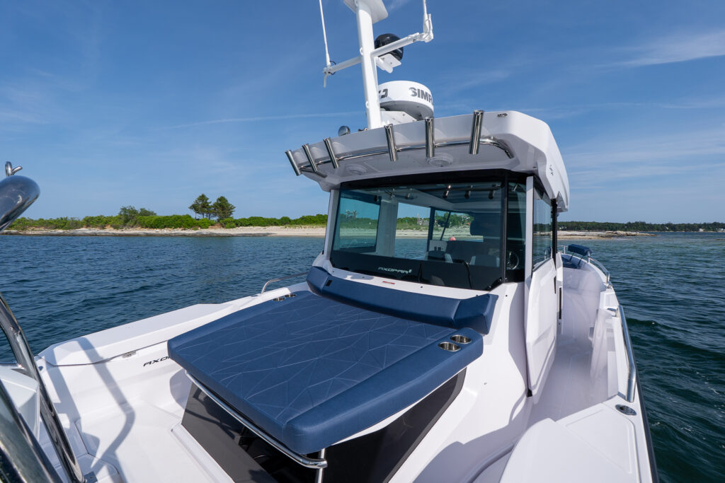 Aft cabin sunpad with Sphere upholstery on an Axopar 29 XC Cross Cabin, with the pilothouse, rod holders, and shoreline in the background.