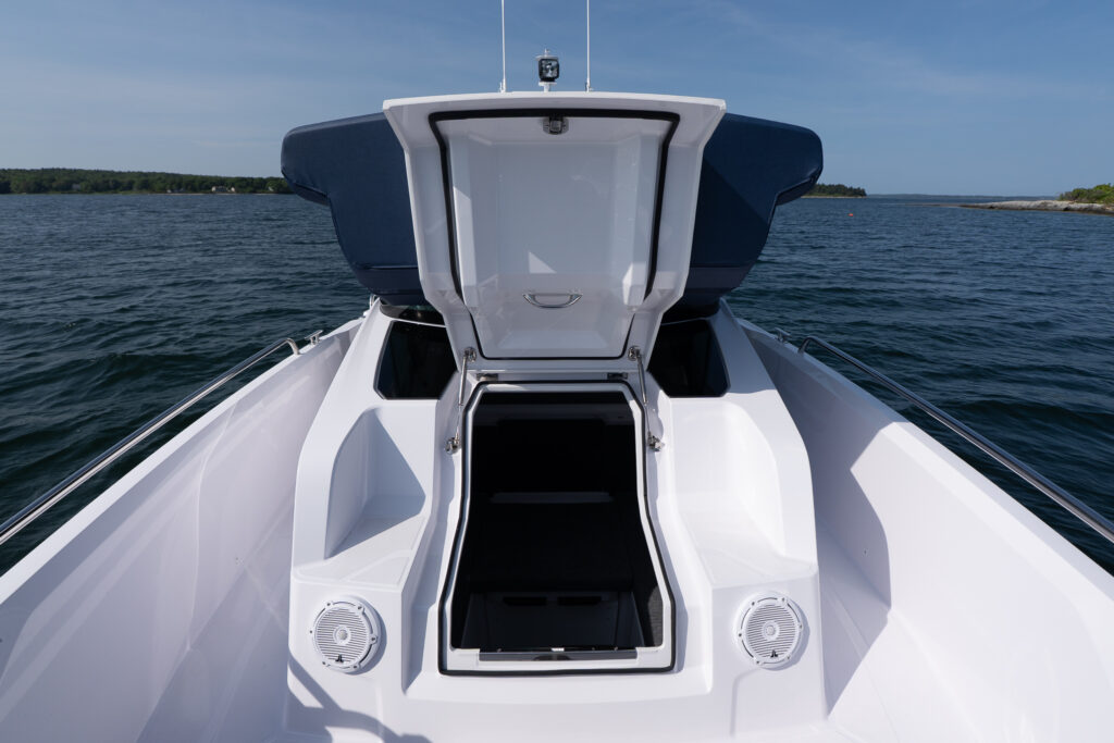 Open forward cabin hatch on an Axopar 29, showing the entrance from the bow area with speakers and seating on both sides while anchored in Casco Bay, Maine.