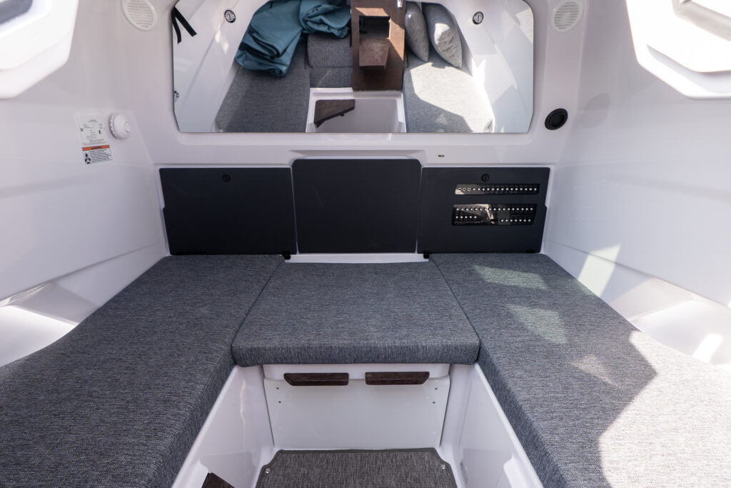 Forward cabin of an Axopar 29 with the Multicabin upgrade, showing cushioned seating and a head compartment hidden discreetly beneath the center section.