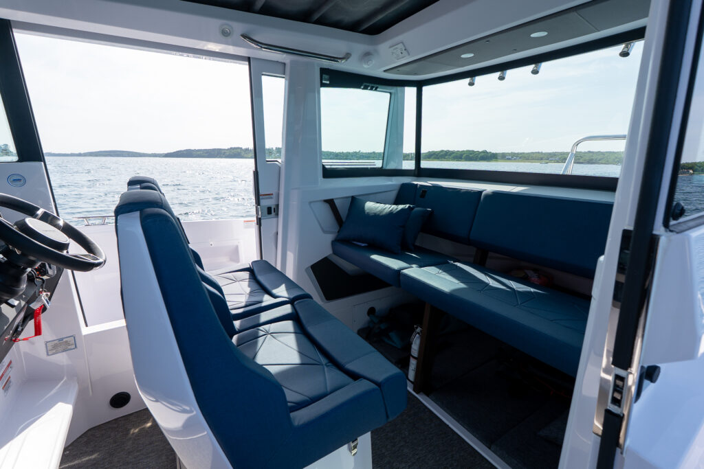 Axopar 29 Stock 34 cabin interior with blue Sphere upholstery and captain’s chairs turned to face the aft bench, overlooking Casco Bay, Maine