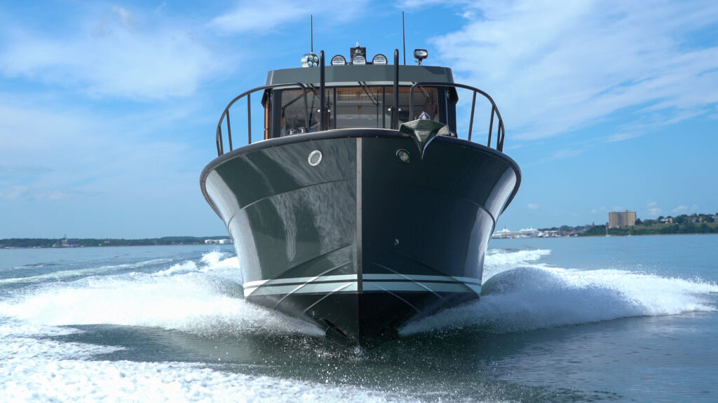 Targa 32 with green hull cruising head-on in Casco Bay, Portland, Maine, with the Eastern Promenade visible in the distance.