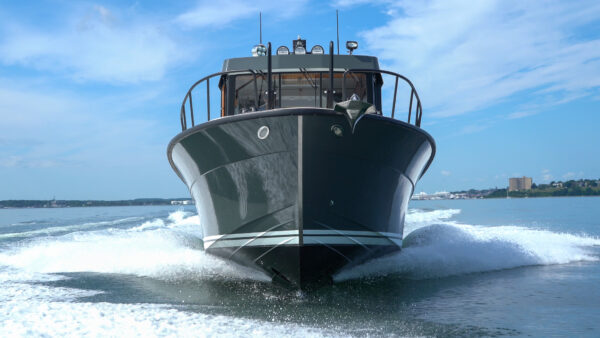 Targa 32 with green hull cruising head-on in Casco Bay, Portland, Maine, with the Eastern Promenade visible in the distance.