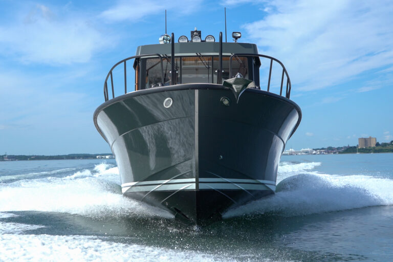 Targa 32 with green hull cruising head-on in Casco Bay, Portland, Maine, with the Eastern Promenade visible in the distance.