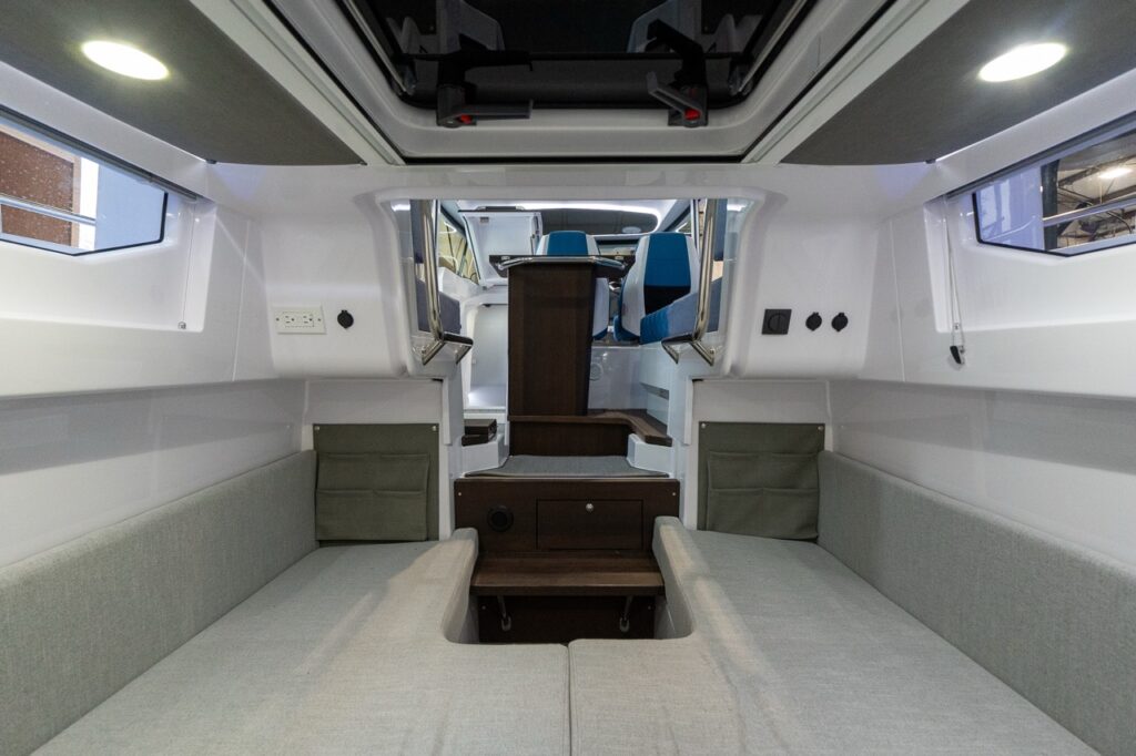 Axopar 37 XC aft cabin interior with twin berth cushions, side windows, overhead hatch, and steps leading forward up into the pilot house.