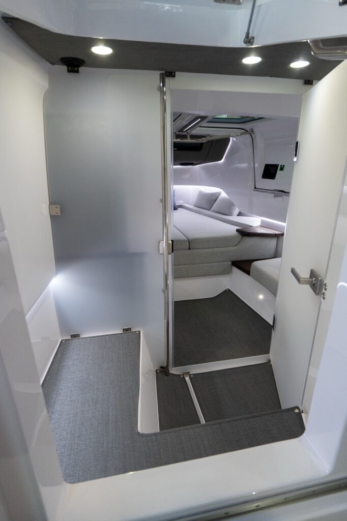 Entryway into the Axopar 37 XC aft cabin with molded steps, grab pole, and a grey upholstered berth visible inside.