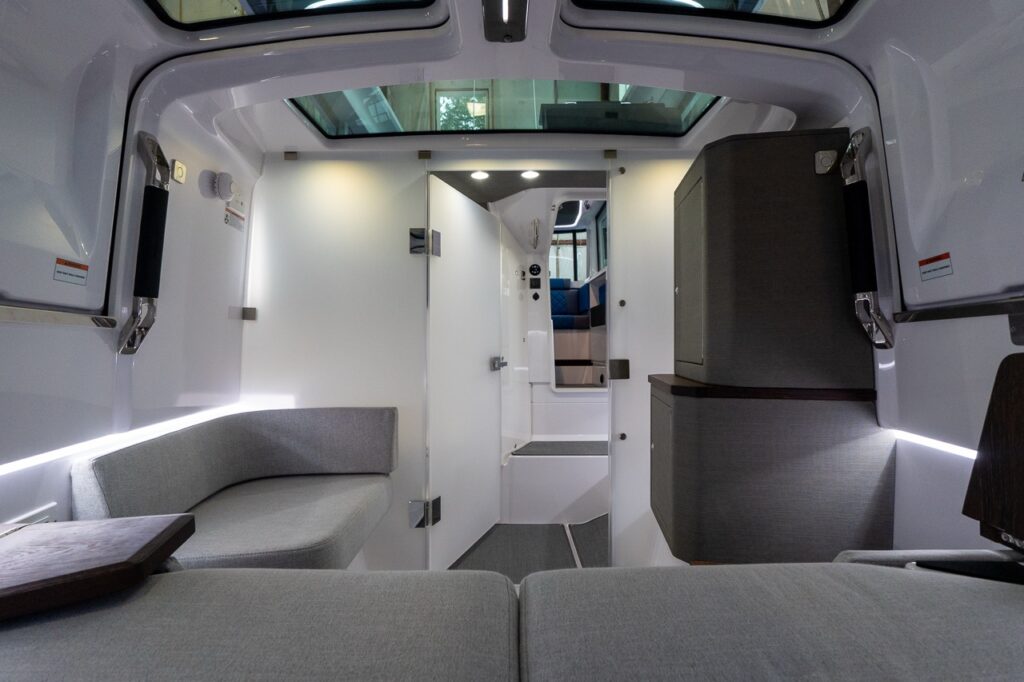Axopar 37 XC aft cabin interior with side sofa seating, tall storage cabinets, LED accent lighting, and roof windows in the closed gullwing doors.