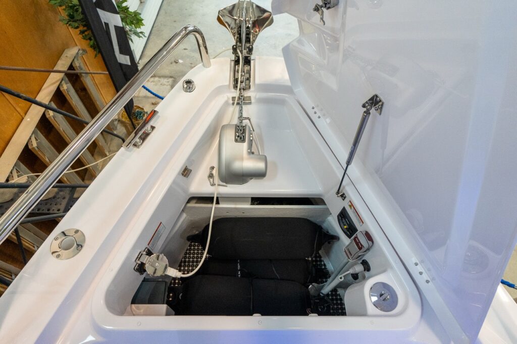 Open anchor locker on an Axopar 37 XC Cross Cabin showing the windlass, anchor chain, bow roller hardware, and deep storage compartment below.