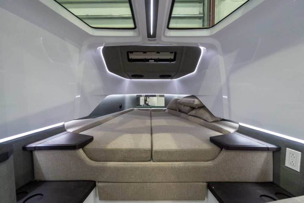Axopar 37 XC Cross Cabin forward sleeping berths with twin cushions, overhead skylights, ambient LED accent lighting, and built-in side shelves.