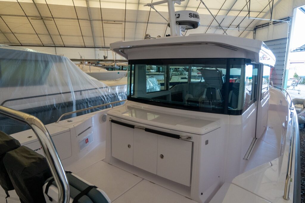 Axopar 37 XC Cross Cabin aft cockpit view showing the aft wet bar cabinet, large pilothouse windows, and wide walkaround side decks.