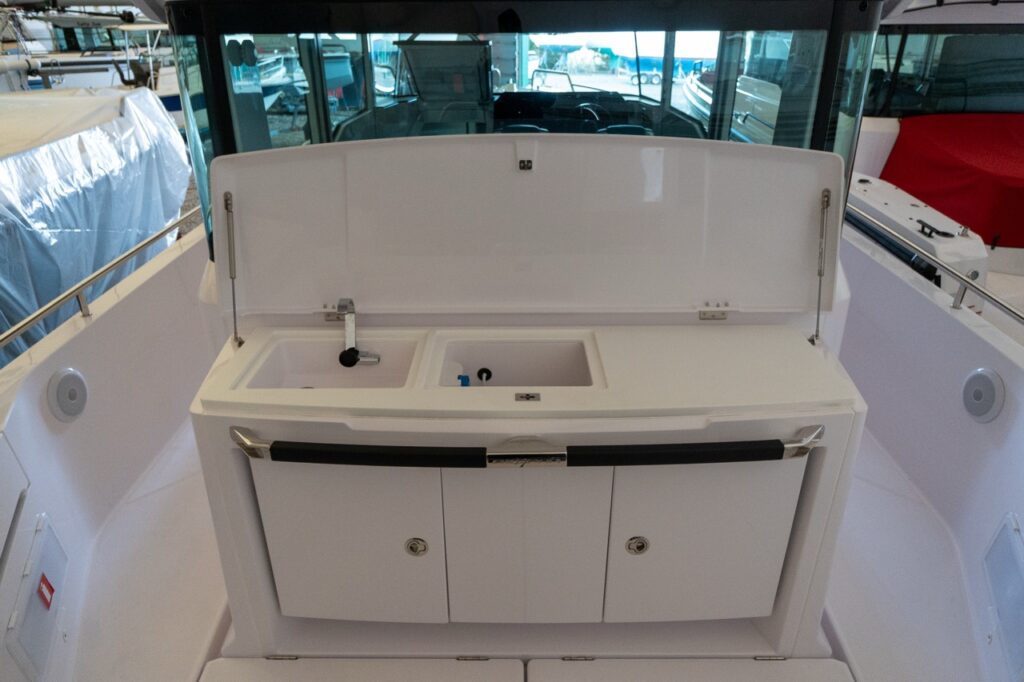 Axopar 37 XC Cross Cabin aft wet bar with the lid open, showing the integrated sink, faucet, and basin compartments above the lower cabinets.
