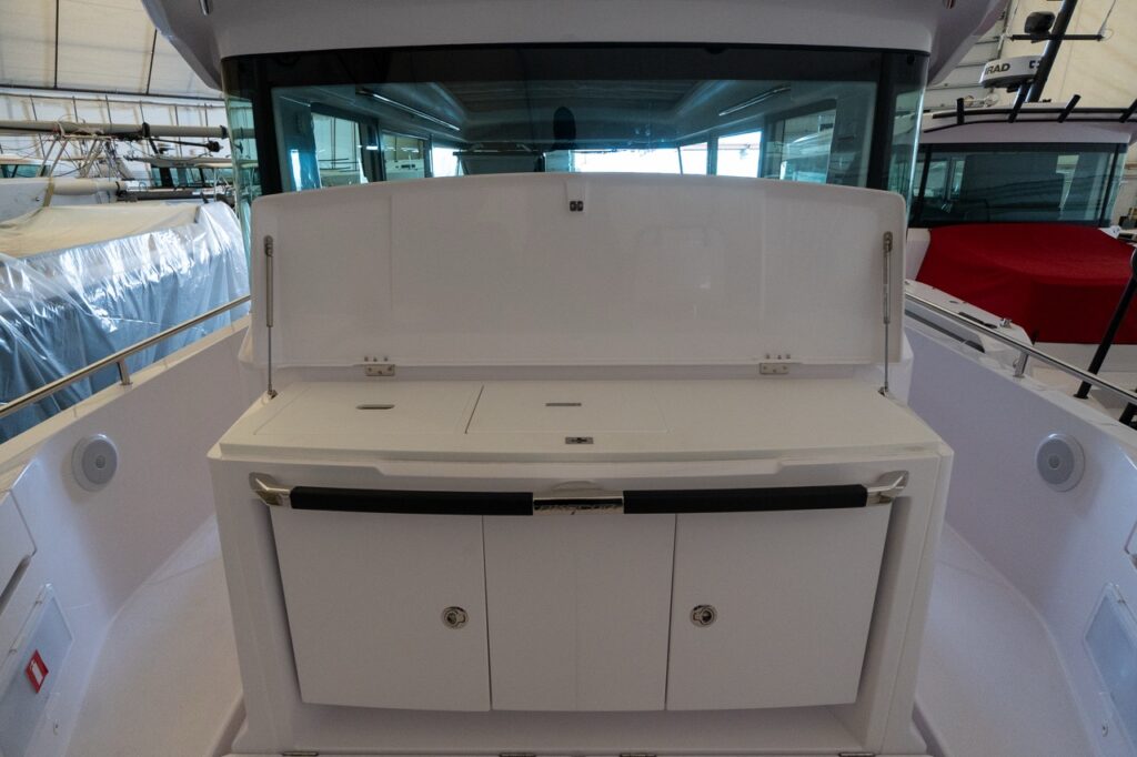 Axopar 37 XC Cross Cabin aft wet bar with the countertop lid raised, revealing the integrated prep/serving surface above the storage cabinets.