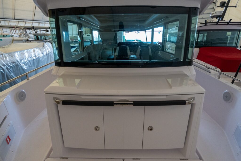 Axopar 37 XC Cross Cabin aft wet bar with the countertop and lower storage cabinets closed, positioned beneath the rear pilothouse window.