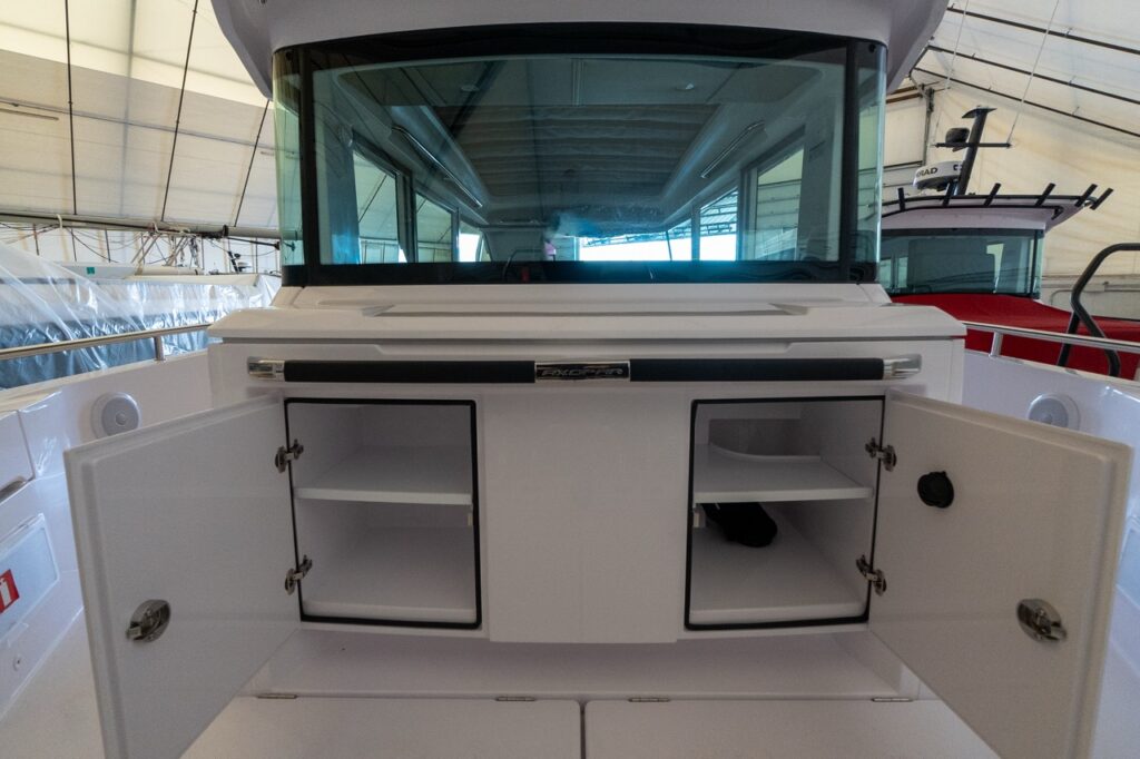 Axopar 37 XC Cross Cabin aft wet bar with the lower storage cabinet doors open, showing built-in shelving beneath the aft-facing counter.