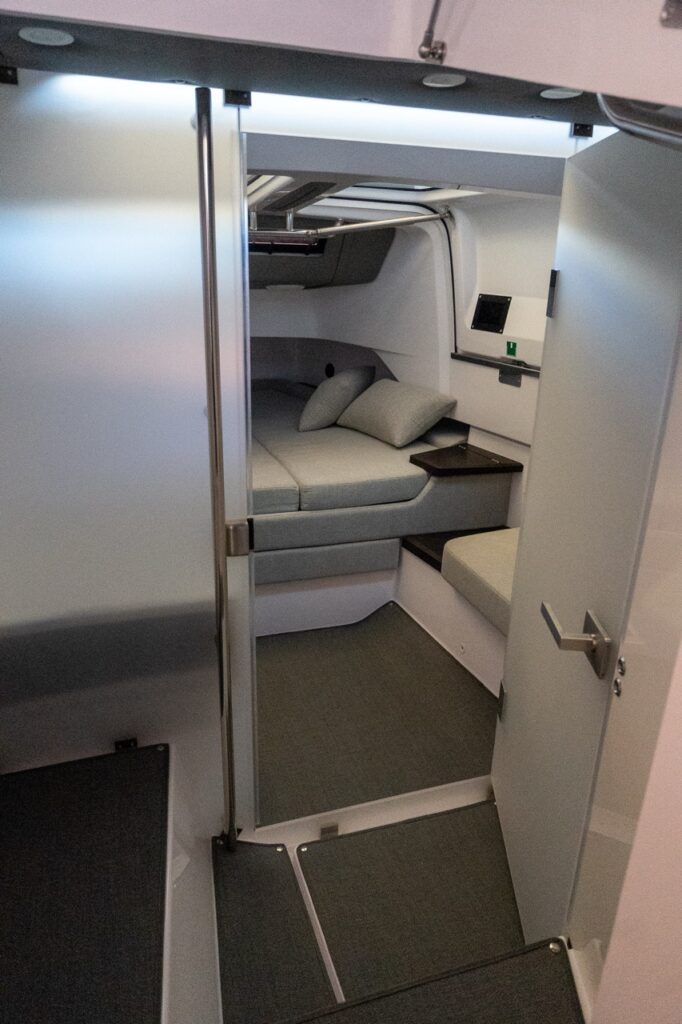 View from the Axopar 37 XC head compartment looking into the forward cabin berths, with the head door open and gullwing windows overhead.