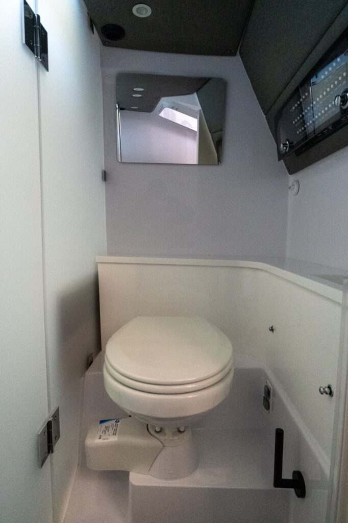 Enclosed head compartment on an Axopar 37 XC Cross Cabin with a marine toilet, privacy door, and mirror.