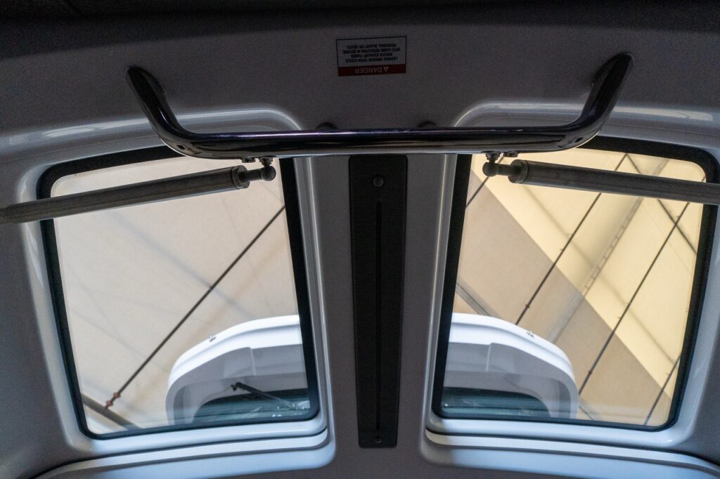 Upward view from the Axopar 37 forward cabin showing twin gullwing door windows, support struts, and the foredeck beyond.