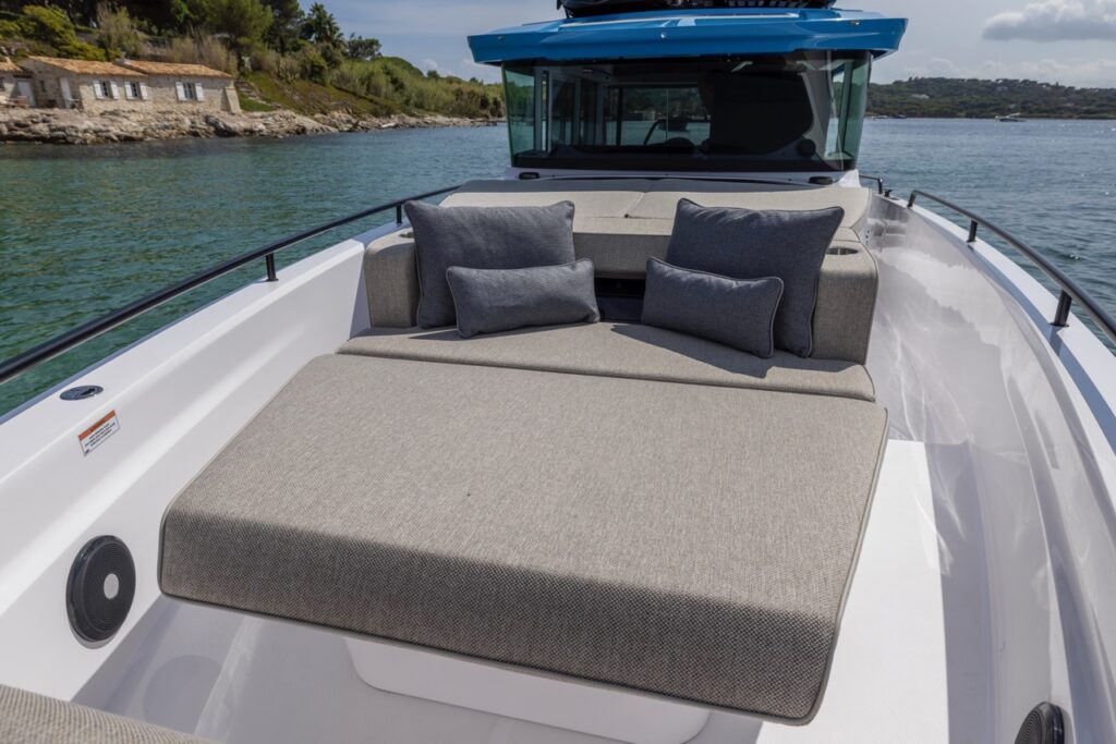 Axopar 37 XC Cross Cabin cruising at speed offshore with a wooded coastline and lighthouse in the background.