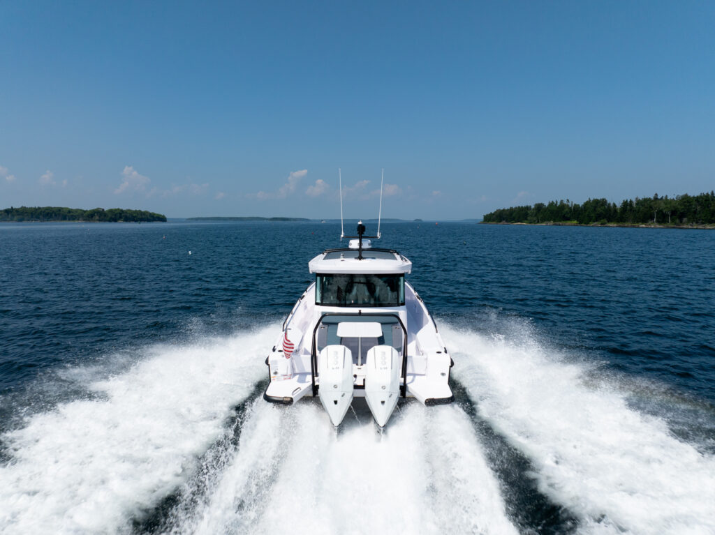 Stern view of an Axopar 37 traveling at cruising speed, leaving a defined wake behind it.