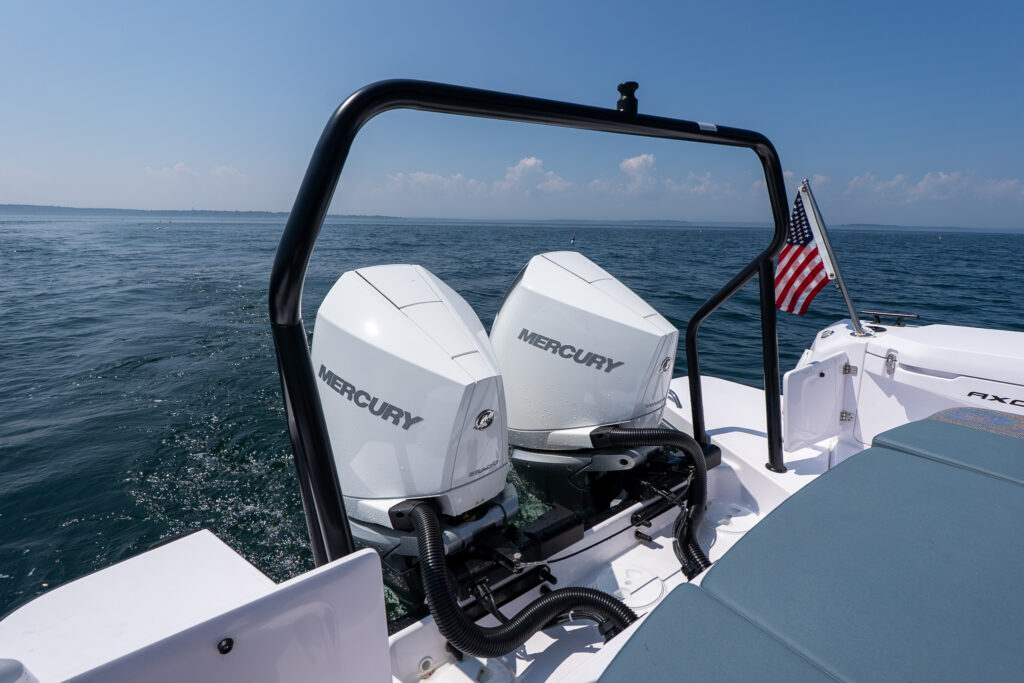 Twin white Mercury outboard engines on the transom of a 37 Axopar, framed by a black tow arch and open ocean backdrop.