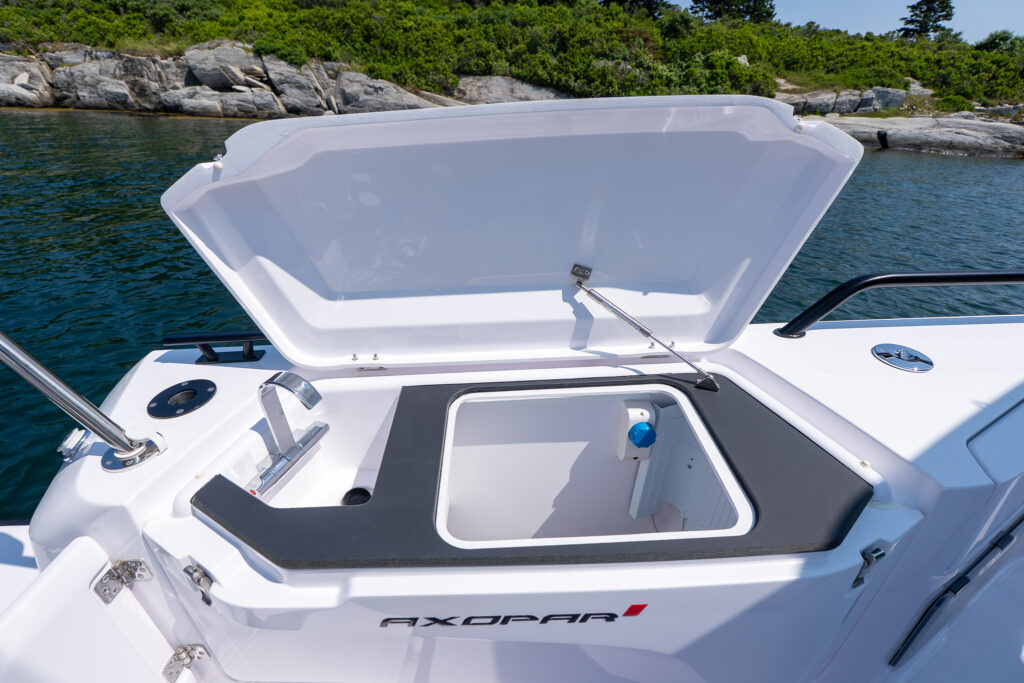 Open fender box wet bar on the aft deck of a 37 Axopar boat, showing an integrated sink and a deep storage bin under a raised hatch.