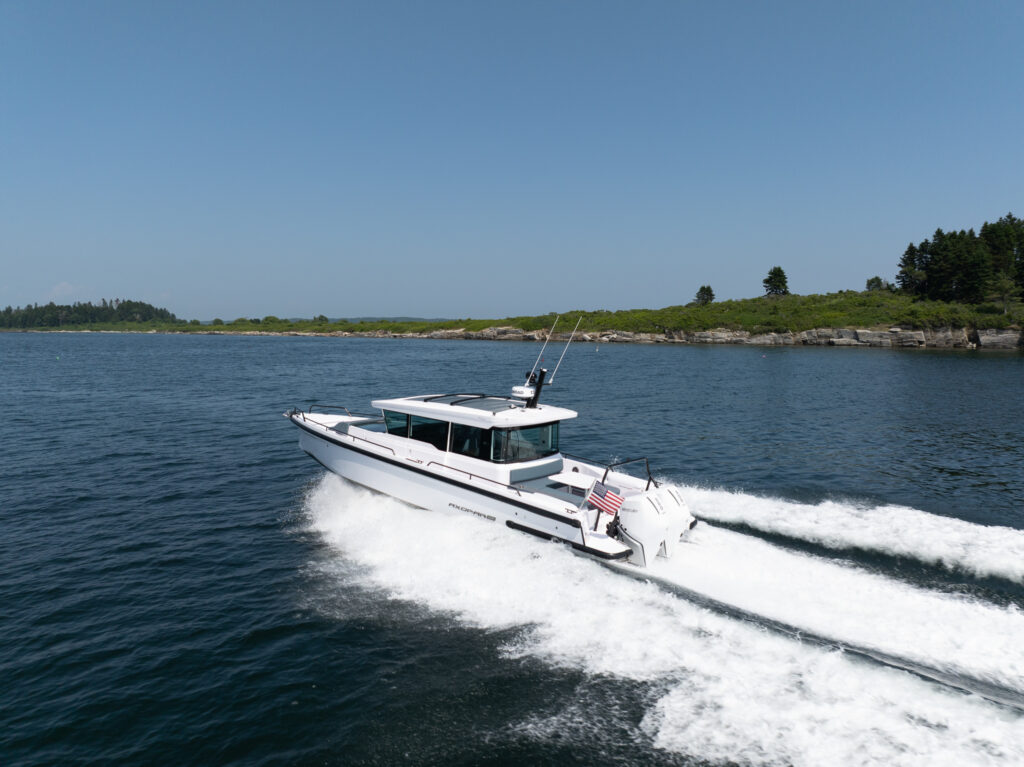 Axopar 37 BRABUS edition cruising at speed along the Casco Bay coastline on a clear day.