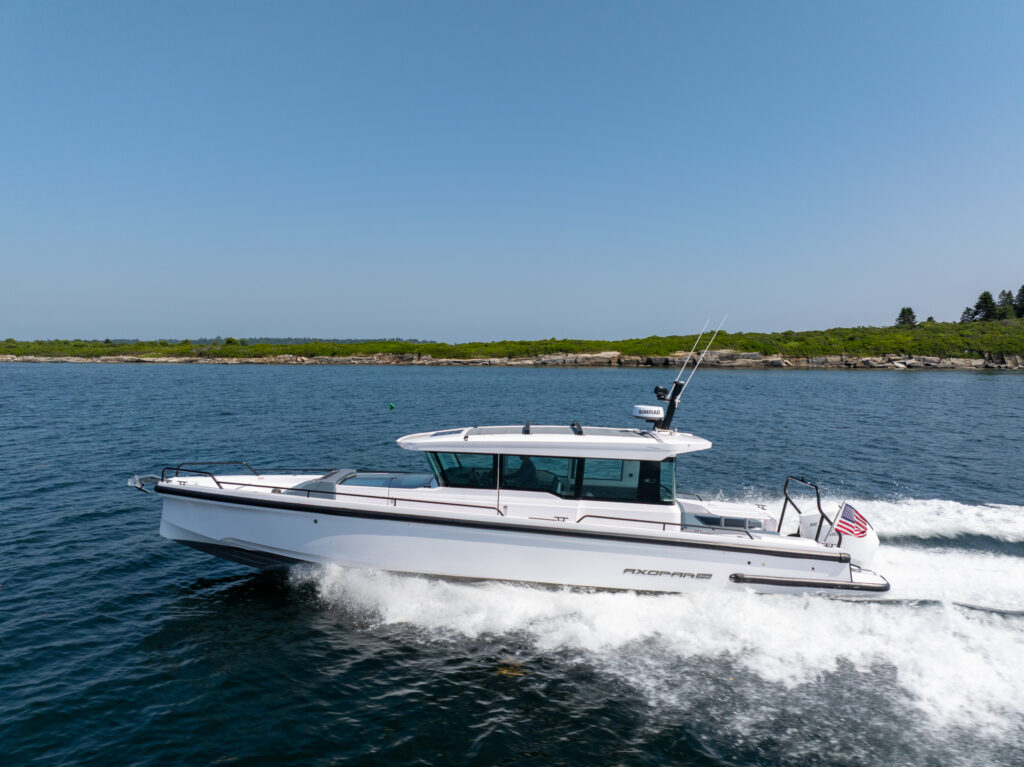 Axopar 37 cruising at speed along the Casco Bay coastline on a clear day.
