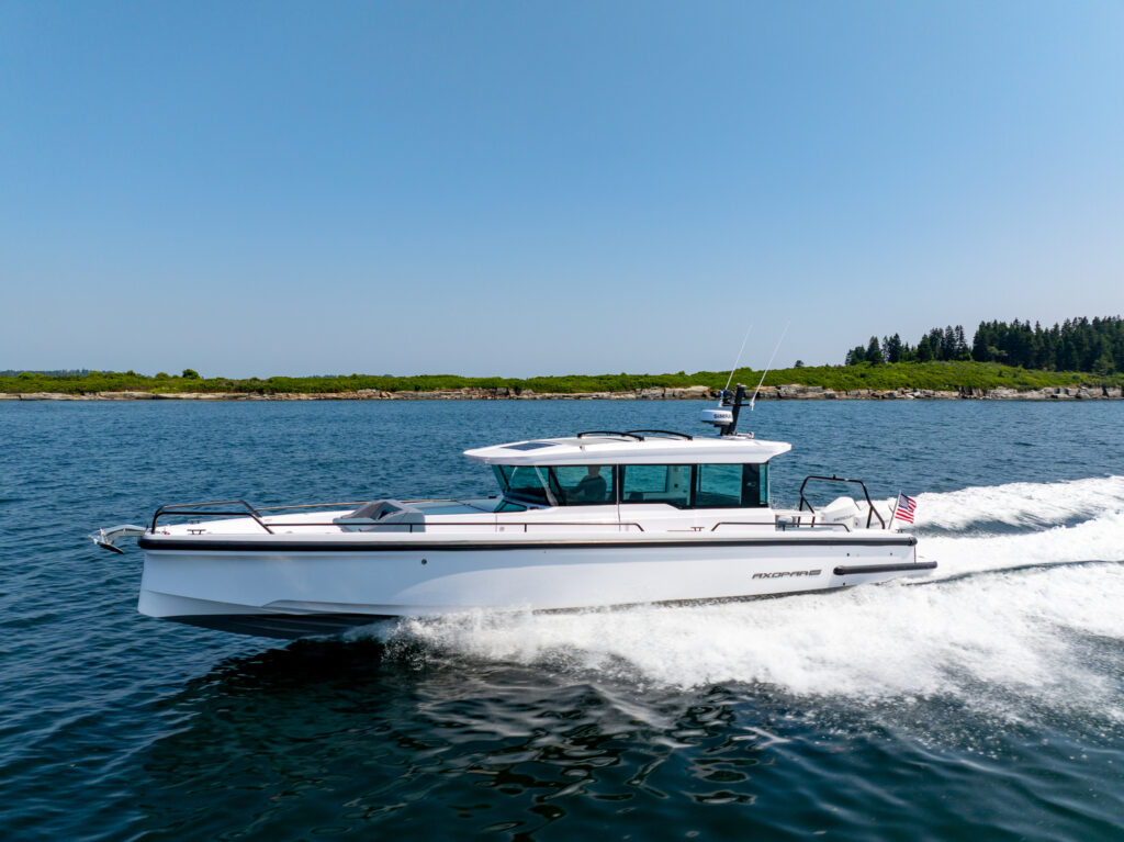 Axopar 37 cruising at speed along the Casco Bay coastline on a clear day.
