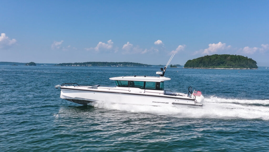Axopar 37 cruising through Casco Bay on a mostly clear day with minimal clouds and an island in the background.