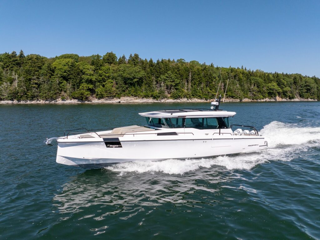 Axopar 45 BRABUS Performance Line speeding across Casco Bay, Maine with a rocky, evergreen shoreline behind it.