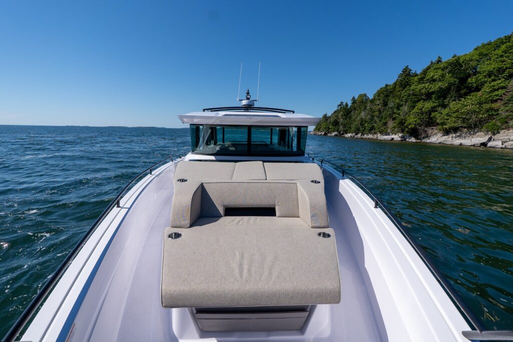 Forward sun lounge and bow seating on an Axopar 45 BRABUS Performance Line with the pilothouse ahead in Casco Bay, Maine.