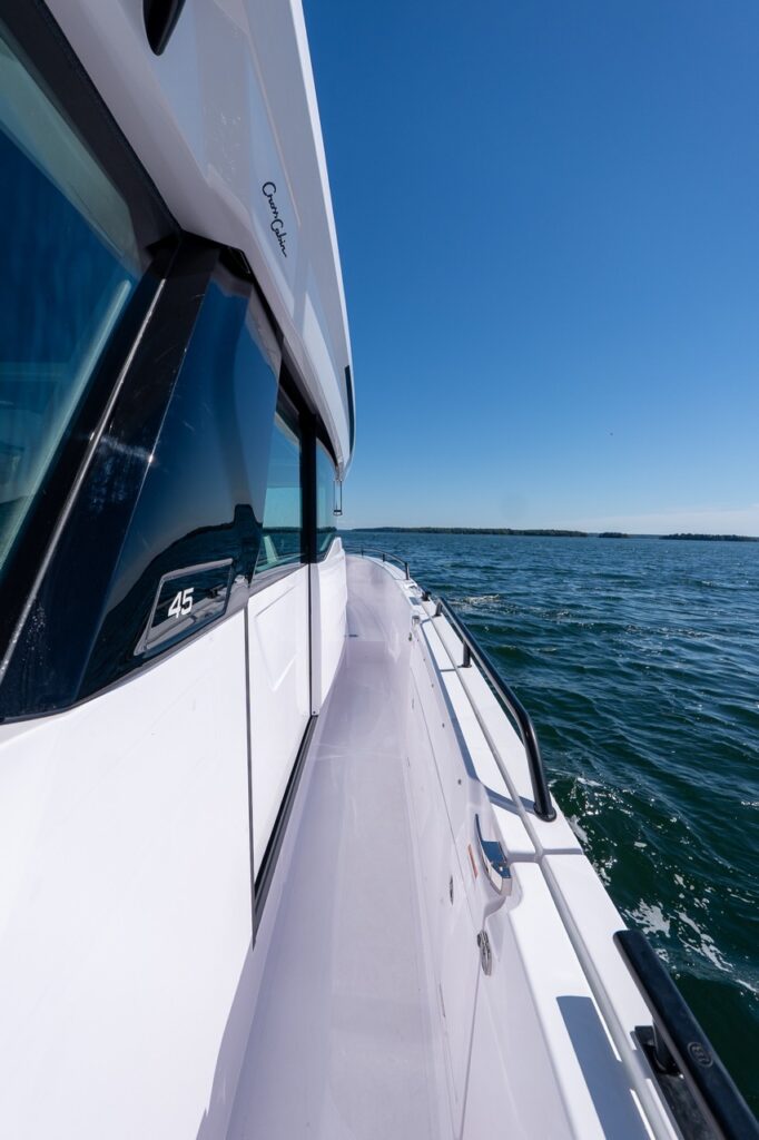 Walkaround side deck along the pilothouse of an Axopar 45 BRABUS Performance Line, with open water ahead in Casco Bay, Maine.