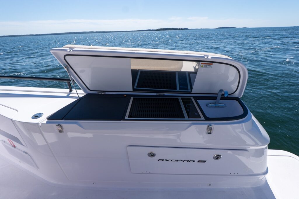 Axopar 45 cockpit wet bar opened to reveal an integrated cooktop and sink, with the ocean in the background in Casco Bay, Maine.
