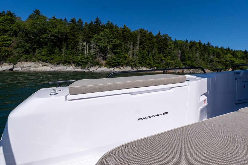 Starboard-side fender box on an Axopar 45 with a cushioned seat, shown with Maine’s rocky shoreline in the background.