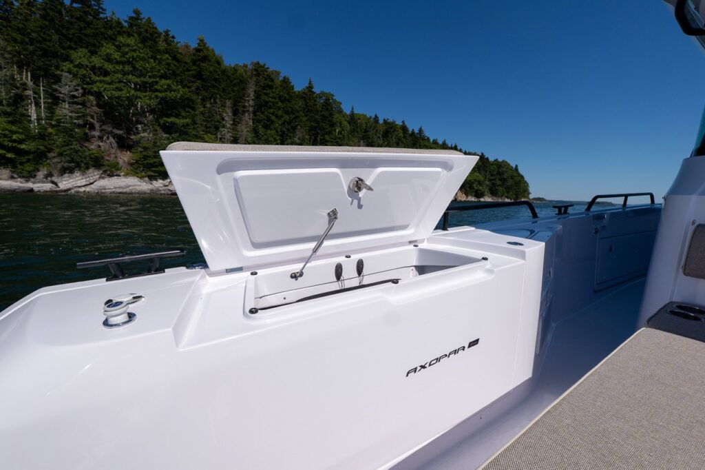 Open starboard-side fender box on an Axopar 45 showing a deep storage compartment, with Maine coastline in the background.