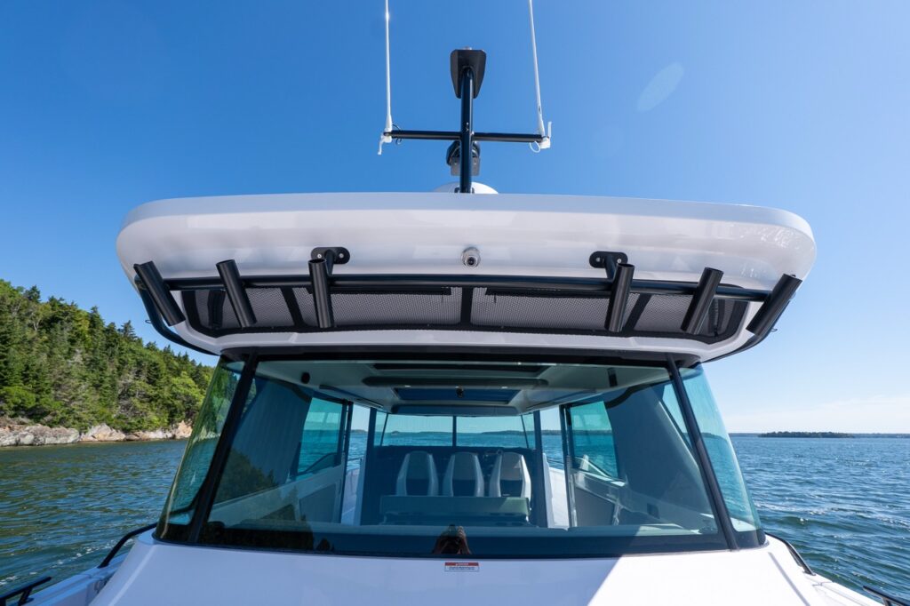 Stern-to-bow view on an Axopar 45 BRABUS Performance Line showing the roof overhang, rod holders, wraparound windshield, and radar mast in Casco Bay, Maine.