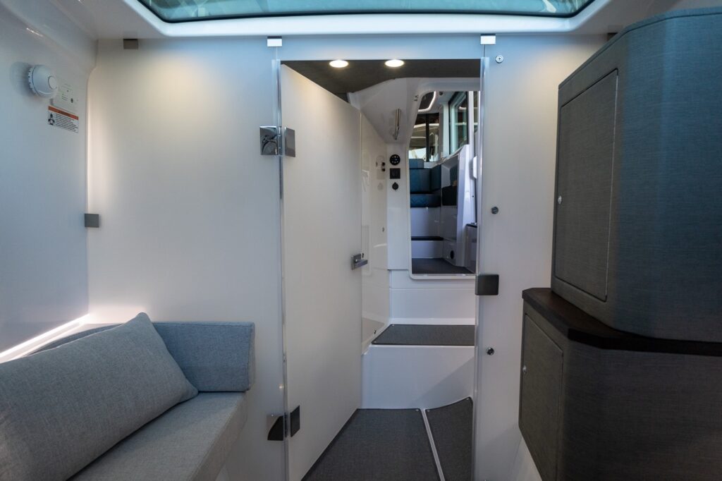 View from the Axopar 37 XC forward cabin looking aft through the open door toward the pilothouse stairs and seating.