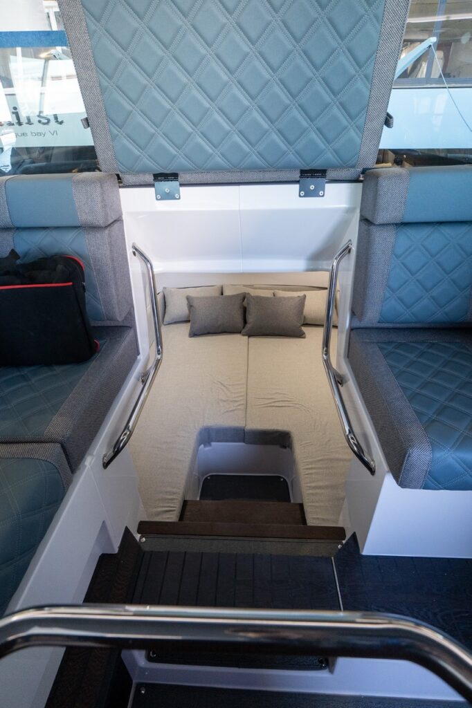 Axopar 37 XC pilothouse view into the aft cabin entrance with the petrol-upholstered aft bench flipped up for access.