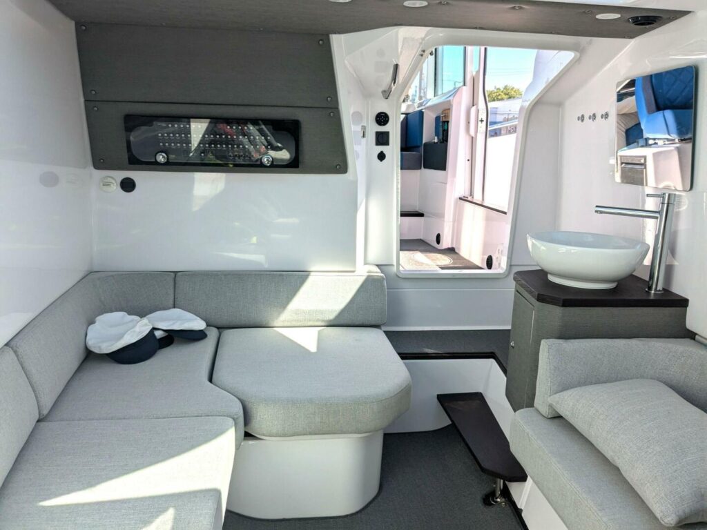 Expanded forward cabin of an Axopar 37 XC Cross Cabin with U-shaped lounge seating, compact sink console, and a hidden head integrated beneath the cushions.