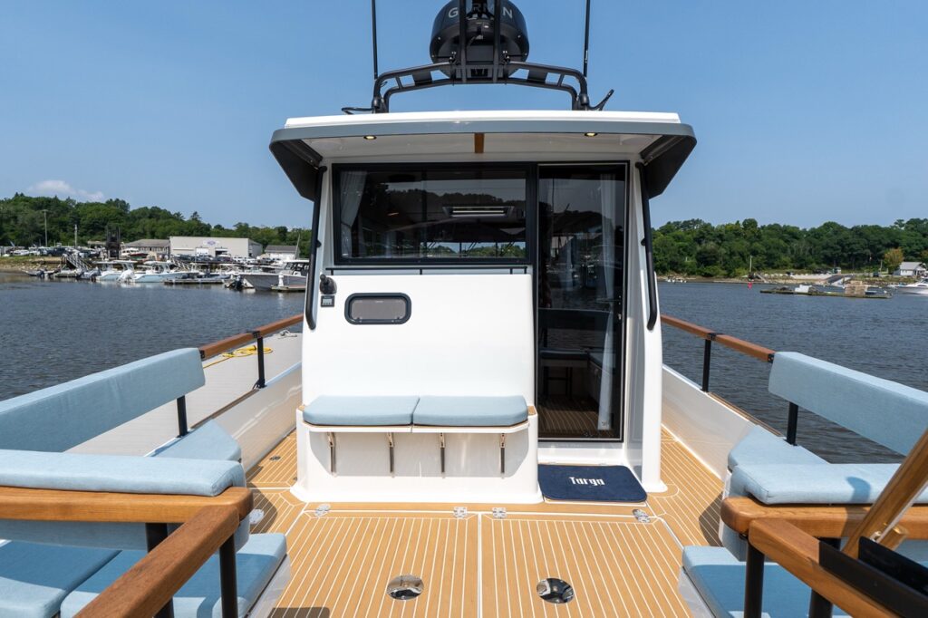 Aft cockpit of the Targa 32 viewed forward, showing port and starboard bench seating, teak-style decking, and the sliding glass door leading into the pilothouse.