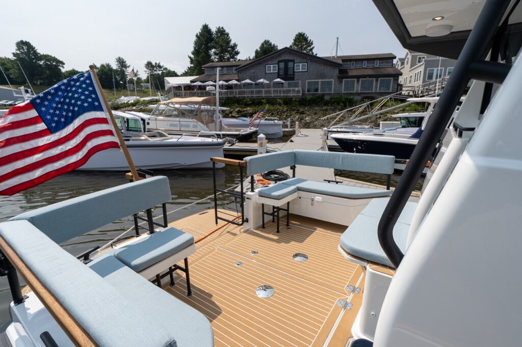 Aft cockpit of the Targa 32 showing wraparound bench seating, teak-style decking, and an American flag at the stern while docked at a marina.