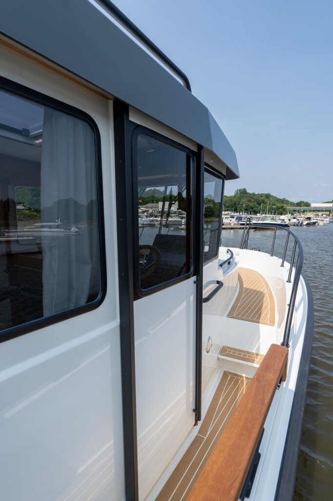 Closed starboard pilot house door on the Targa 32 with the protected side deck and teak-style walkway visible alongside the cabin.