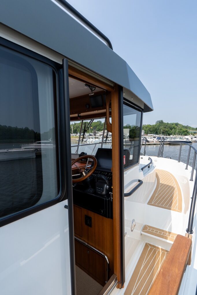 Open starboard pilot house door on the Targa 32 showing the helm station and the teak-style side deck walkway.