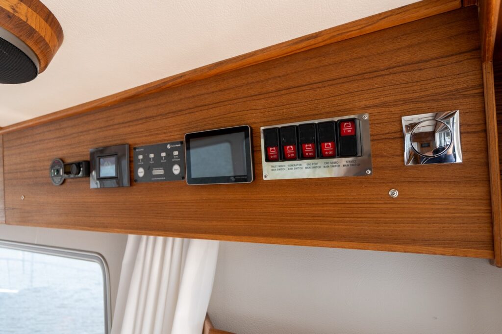 Close-up of the overhead electrical control and monitoring panel integrated into the teak cabinetry in the Targa 32 pilot house.